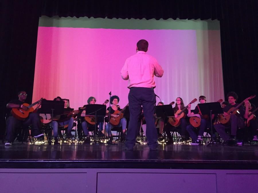 Dave Hagan, Guitar/Band, conducts high school guitar students. Hagan explained that each group of students performs a ten minute set. This also depends on what level students are at. Older students play longer pieces, while younger students play shorter pieces. 