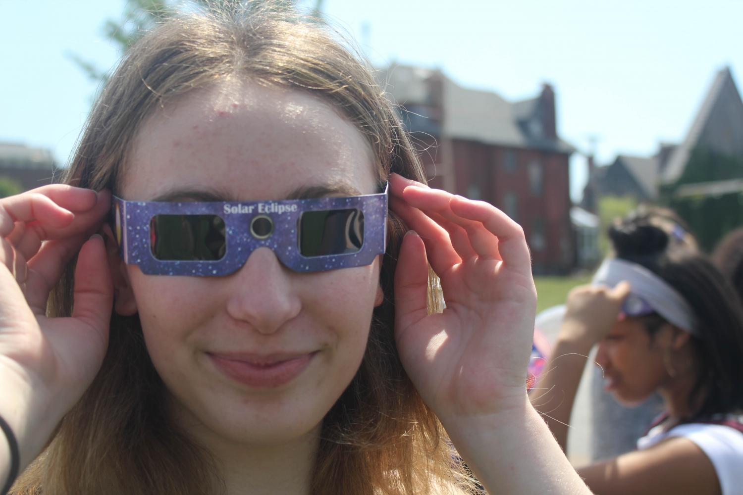 Amirah Bauder puts on her glasses to watch the eclipse.  Bauder says her favorite part was how it was dark even though it was in the afternoon.  It was really cool to get to see the sun slowly get covered by the moon, and the sun slowly disappear, but my favorite was seeing my surroundings get darker, because it felt like night, Bauder said.