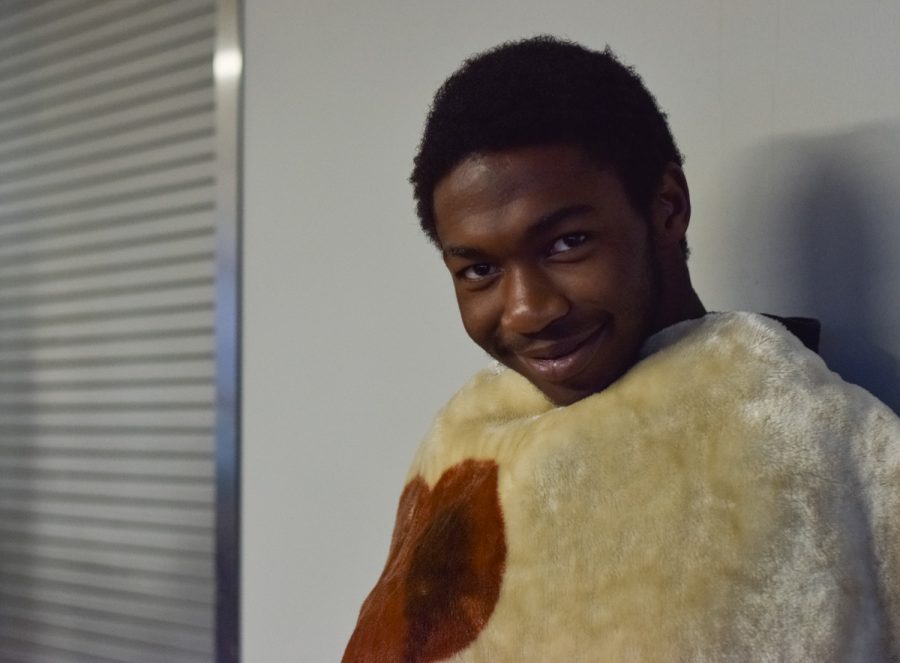 Sophomore Elijah Moye waits for the bell wrapped in a teddy bear blanket in the cafeteria. Im participating in spirit week because I just really wanted to get into the feel of this month, said Moye.