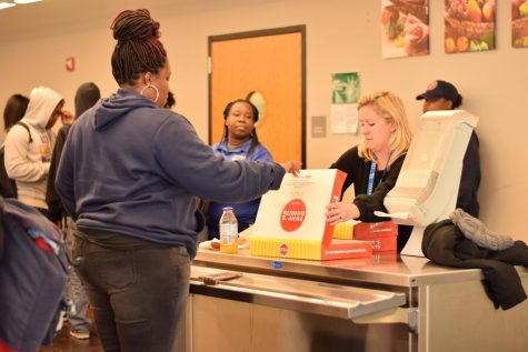 Guidance counselor Kim Campbell distributes donuts during an attendance incentive party. 