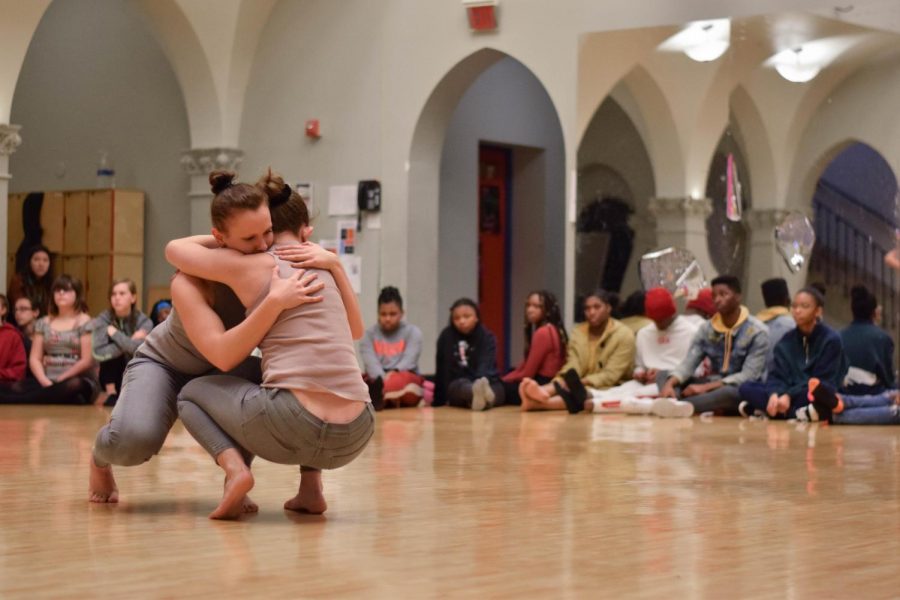 Students from both high school and middle school spectate as Iowa University students perform a piece representing reaching out and supporting a friend through their hardships to demonstrate how dance can be used to express emotion and to tell stories.