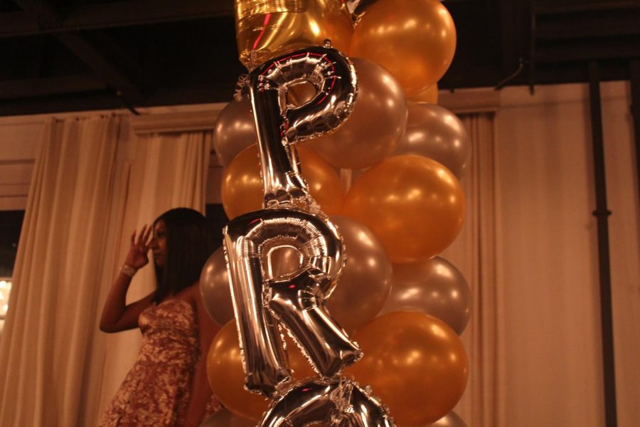 A balloon arrangement with the word prom decorates the stage while senior Charlie Anderson dances on the stage platform.