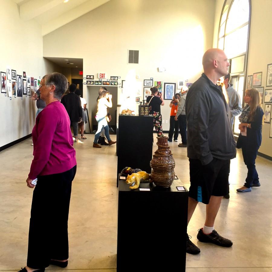 Crowds of people arrive in the Sun Theatre Mezzanine on April 23. Artist Ivy Beckenholdt father, Michael Beckenholdt (left), stands off to the side. Middle school artwork was featured in the main lobby of the GCAA lobby, "Walk A Mile in Their Shoes" artwork was featured both between the Sun Theatre and GCAA main building and inside the lobby of the Sun Theatre. High school artwork was featured in the upstairs Mezzanine. 