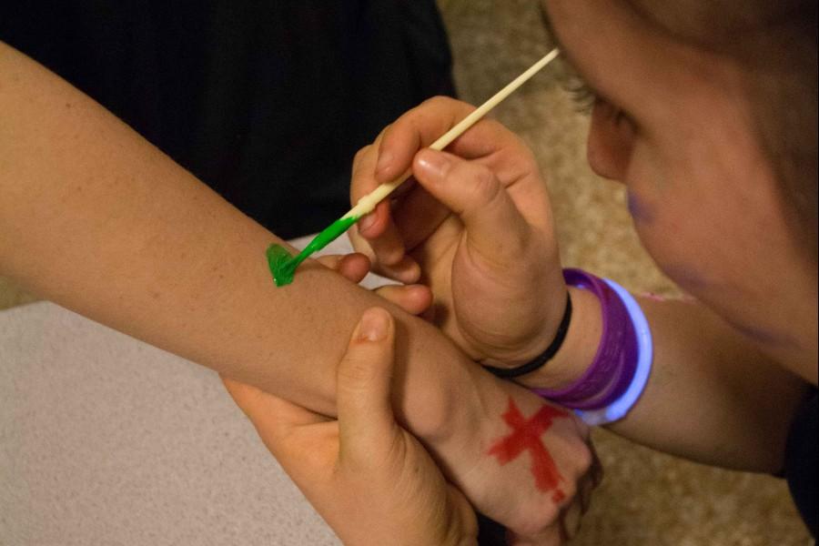 At the high school glow party, May 2nd, students help each other with the paint.