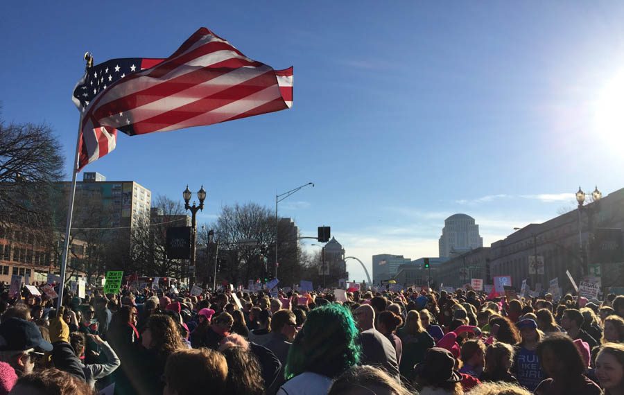 Protesters gather around an American flag, near the start of the march at Union Station. Nearly 20,000 people marched from Union Station to the Arch in support of women's rights. 