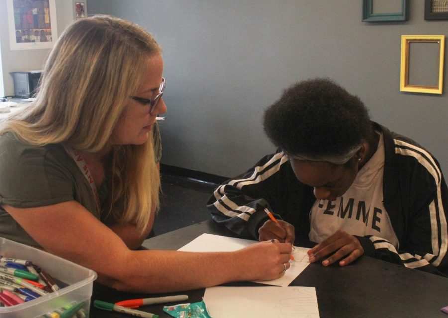 Kelly Baker, visual arts teacher, instructing a advising a student on what to do.