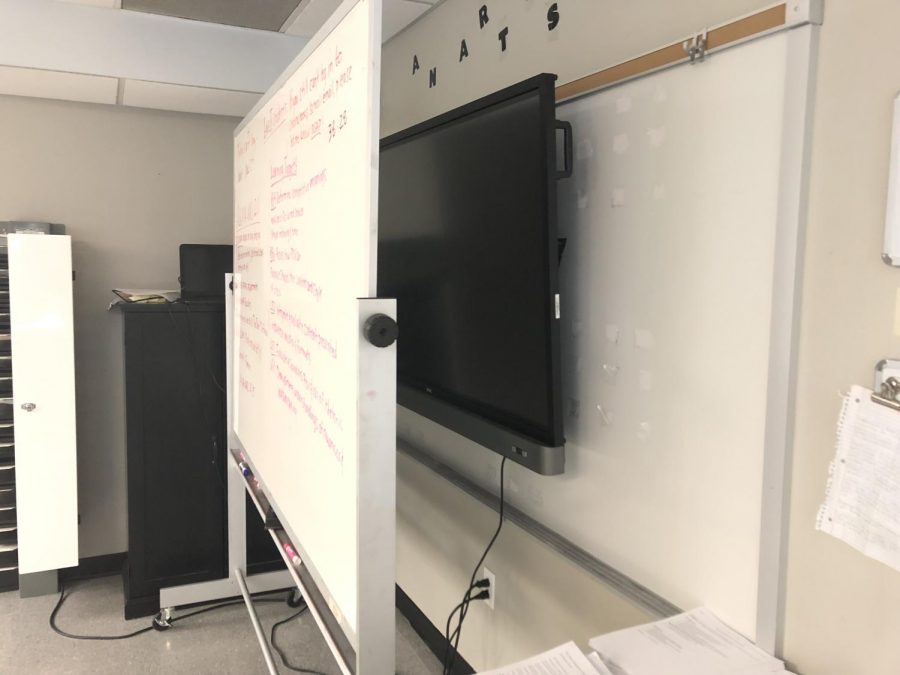 A portable whiteboard stands in front of English teacher Dana Chamberlain's BenQ Board after it was mounted on her board without being connected. Before science teacher Bradford Buck came and helped her get it connected, she still relied on her old projector, using the whiteboard in place of the BenQ for several weeks. 