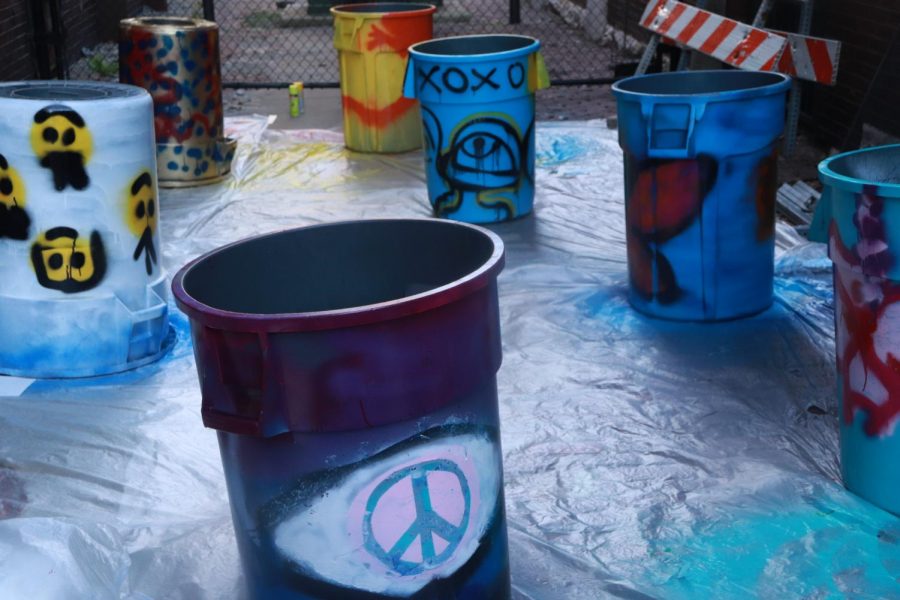 Students let their newly painted unfinished trash bins dry. Each bin with a unique design and/or pattern.